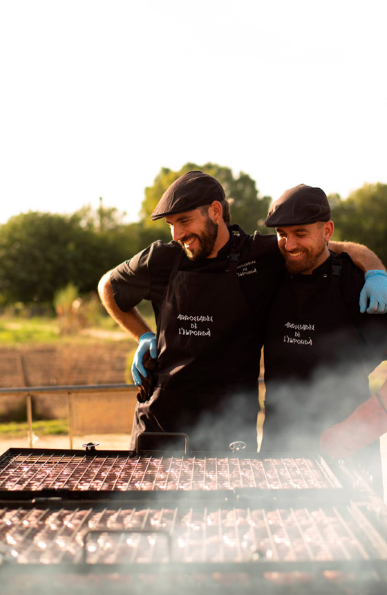 Dos cocineros a domicilio de Arrozadas del Empordà preparando carne a la brasa para un evento
